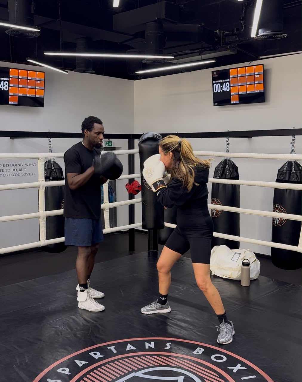 Coach Allid coaching a client on the heavy bag inside a boxing gym