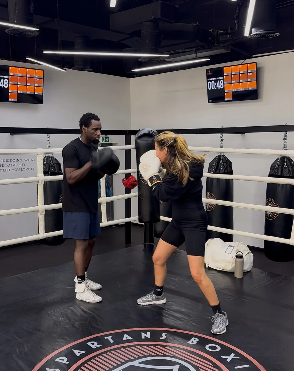Coach Allid coaching a client on the heavy bag inside a boxing gym